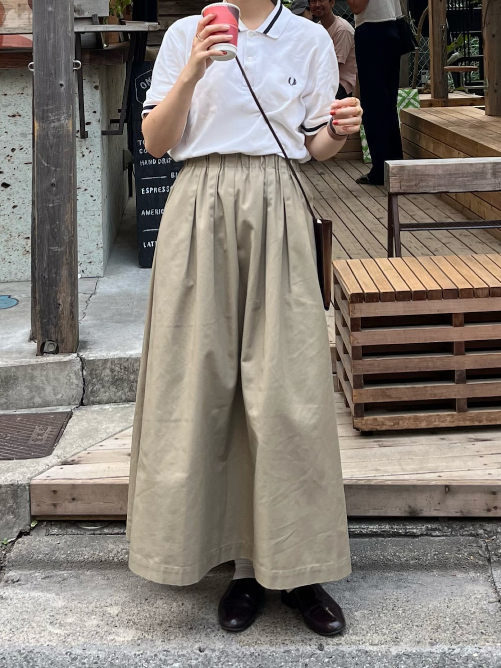 ホワイト系のポロシャツ、ベージュ系のスカート、ブラウン系のドレスシューズを着用したレディースの夏コーディネートの2枚目の写真