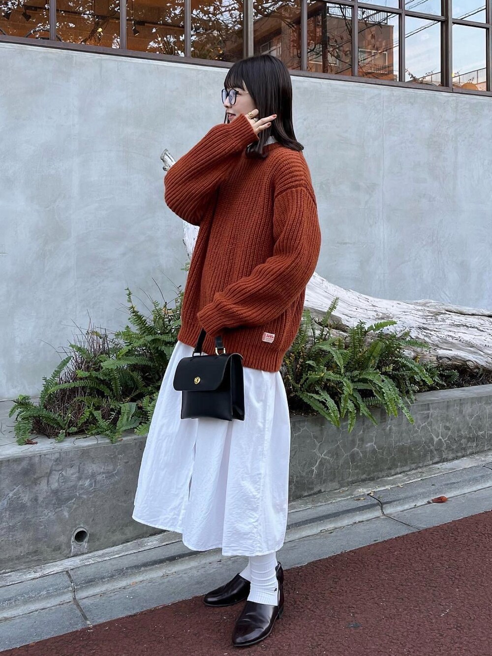 イエロー系のニット/セーター、ブラック系のショルダーバッグ、ホワイト系のワンピースを着用したレディースの秋コーディネートの2枚目の写真
