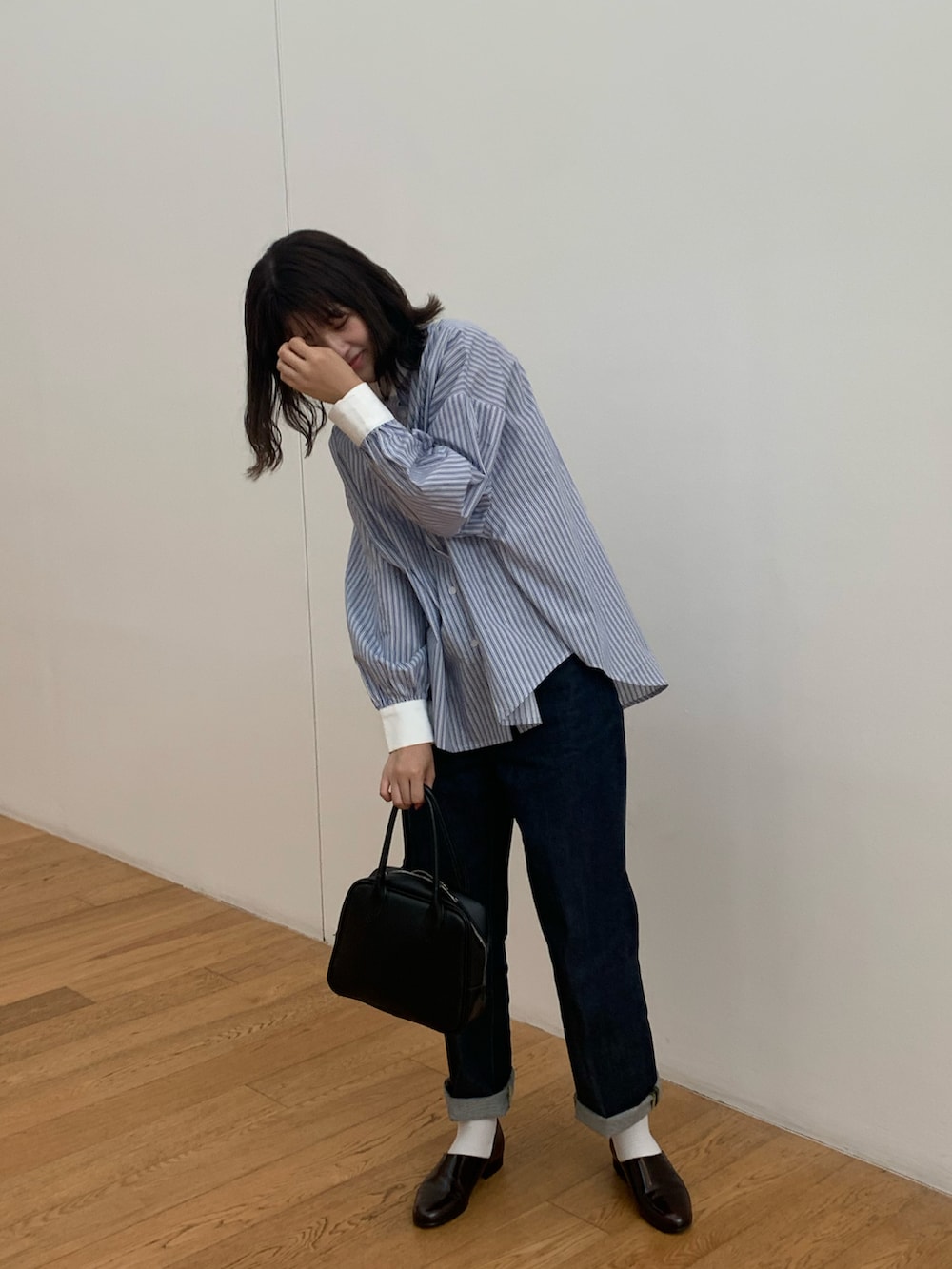 ブルー系のシャツ/ブラウス、ブルー系のデニムパンツ、ブラック系のハンドバッグを着用したレディースの春コーディネートの3枚目の写真