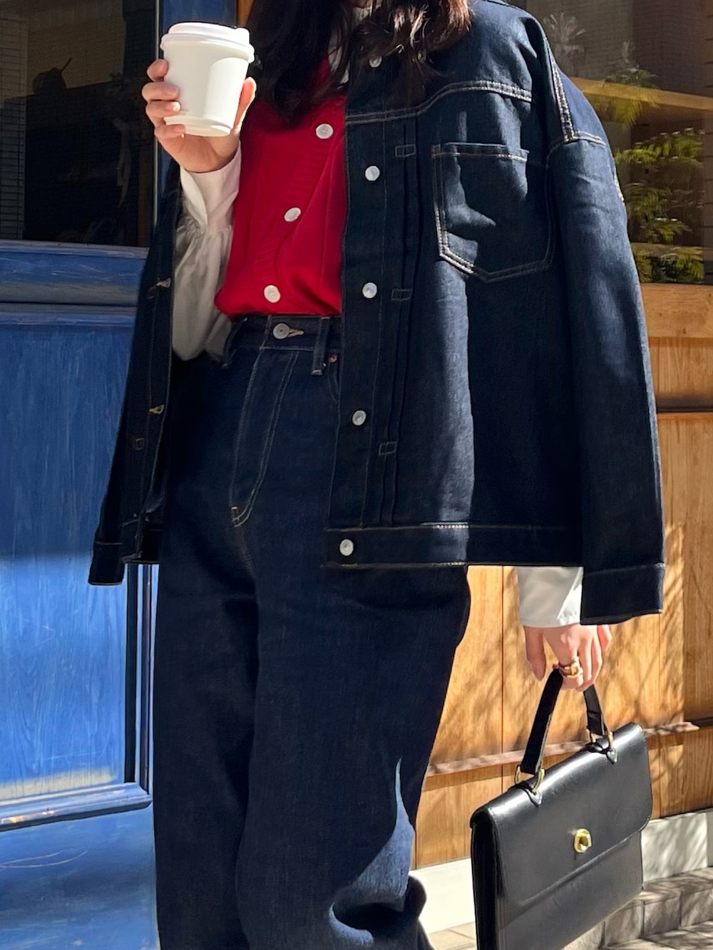 ブルー系のデニムパンツ、ブルー系のデニムジャケット、ブラック系のショルダーバッグを着用したレディースの春コーディネートの2枚目の写真