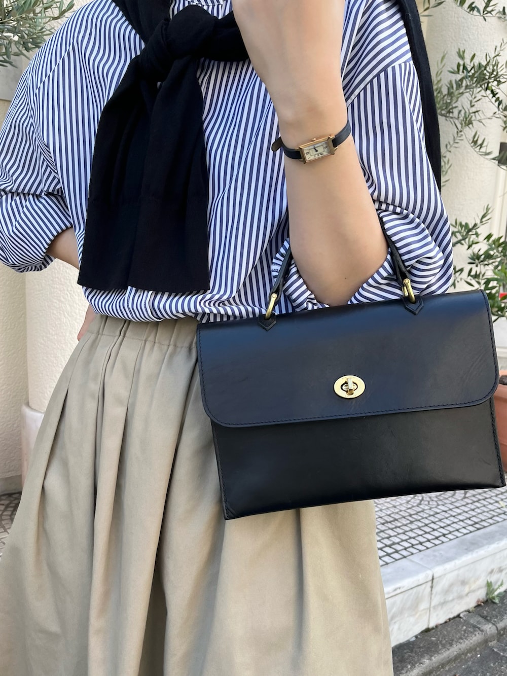 ベージュ系のスカート、ブルー系のシャツ/ブラウス、ブラック系のショルダーバッグを着用したレディースの春コーディネートの2枚目の写真