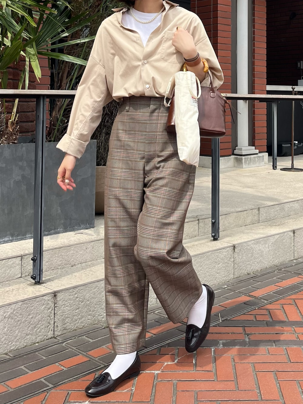 ブラウン系のローファー、ブラウン系のハンドバッグ、ベージュ系のパンツを着用したレディースの春コーディネートの2枚目の写真