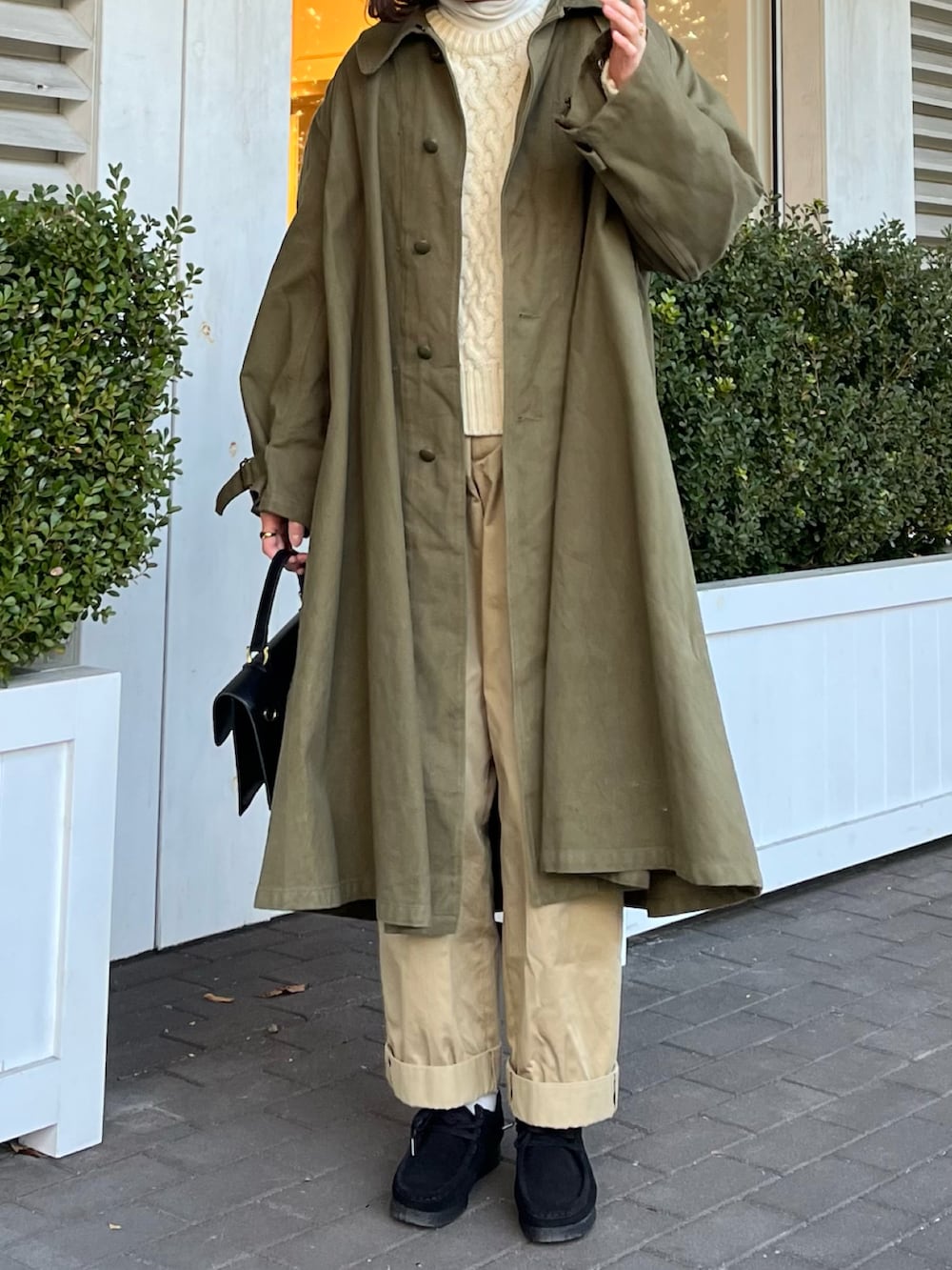 ホワイト系のニット/セーター、ブラック系のモカシン/デッキシューズ、ベージュ系のチノパンツを着用したレディースの冬コーディネートの2枚目の写真