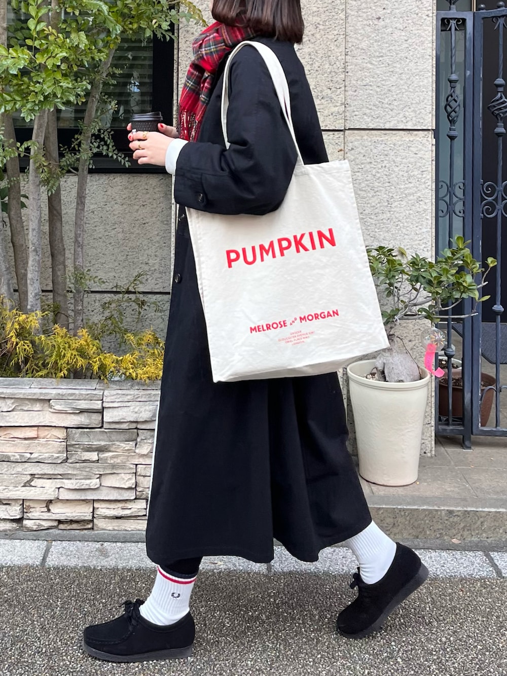 ホワイト系のワンピース、ブラック系のモカシン/デッキシューズ、ブラック系のトレンチコートを着用したレディースの冬コーディネートの2枚目の写真