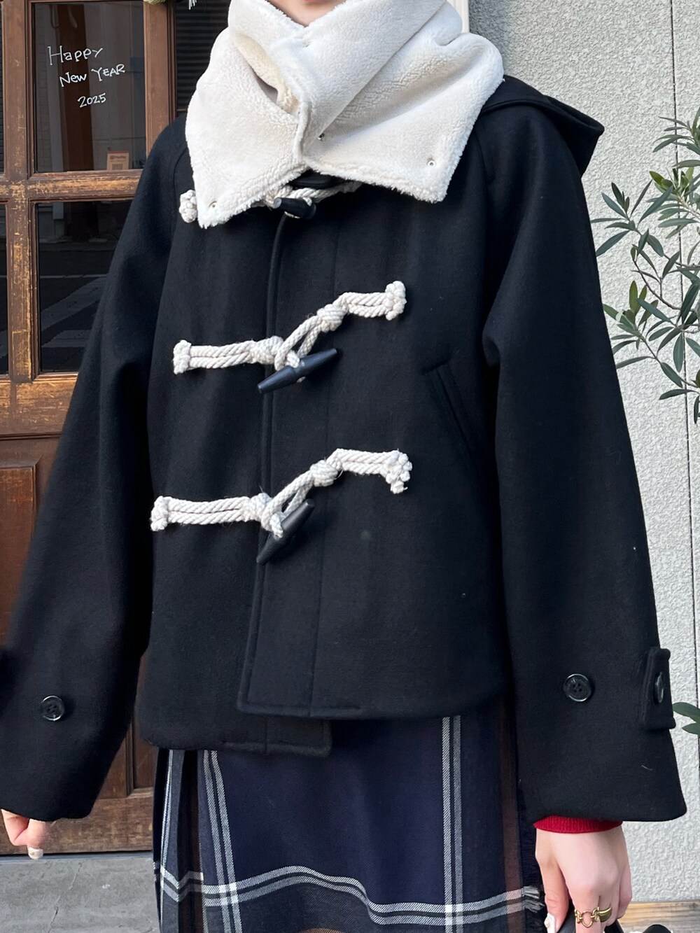 ブラック系のショルダーバッグ、ブルー系のスカート、ブラック系のダッフルコートを着用したレディースの冬コーディネートの2枚目の写真