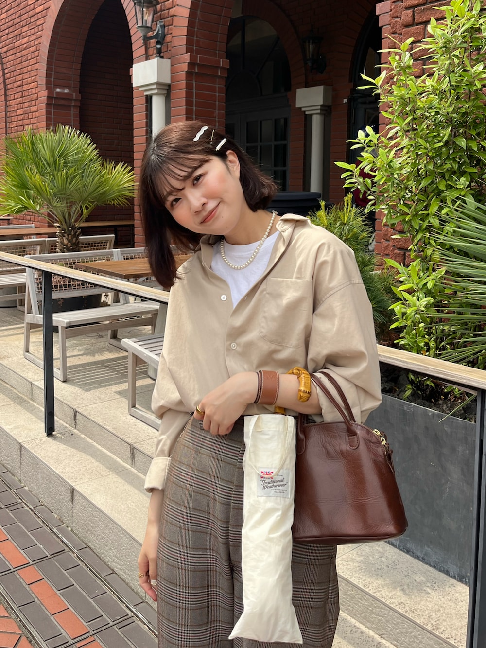 ブラウン系のローファー、ブラウン系のハンドバッグ、ベージュ系のパンツを着用したレディースの春コーディネートの3枚目の写真