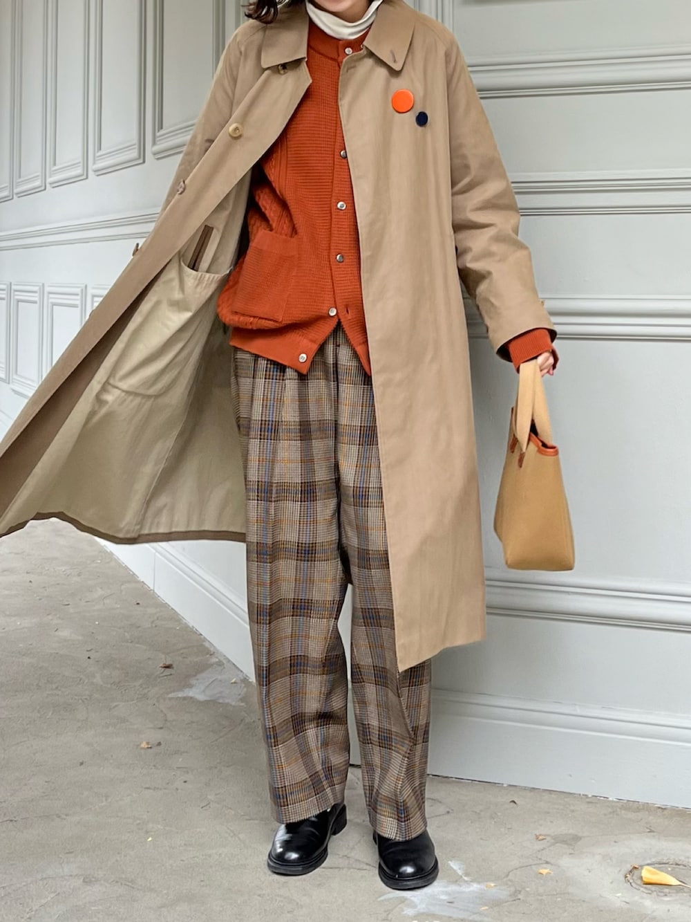 グリーン系のトートバッグ、ブラウン系のスラックス、ベージュ系のステンカラーコートを着用したレディースの冬コーディネートの2枚目の写真