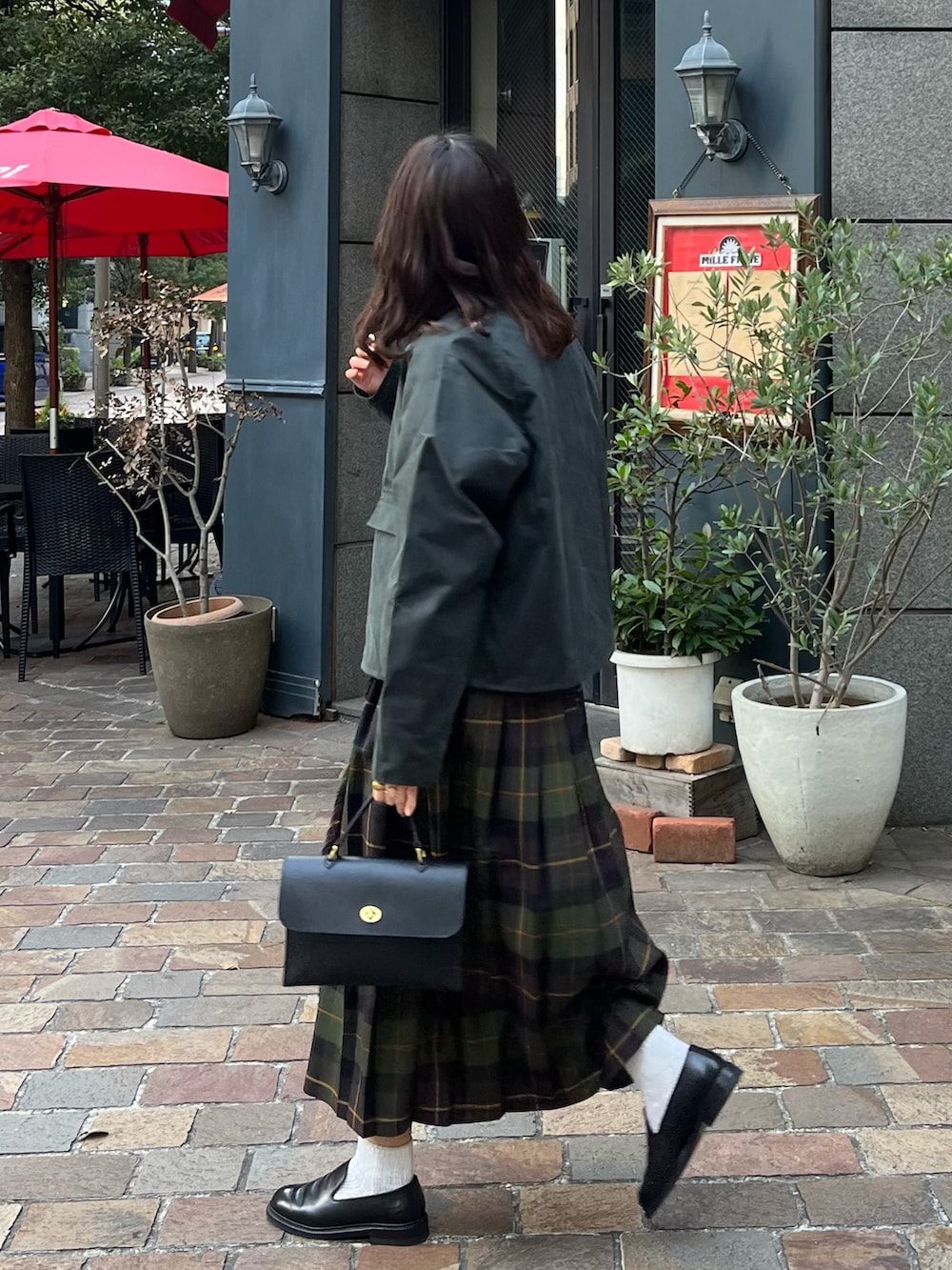 ブラック系のショルダーバッグ、グリーン系のスカート、グリーン系のブルゾンを着用したレディースの冬コーディネートの2枚目の写真