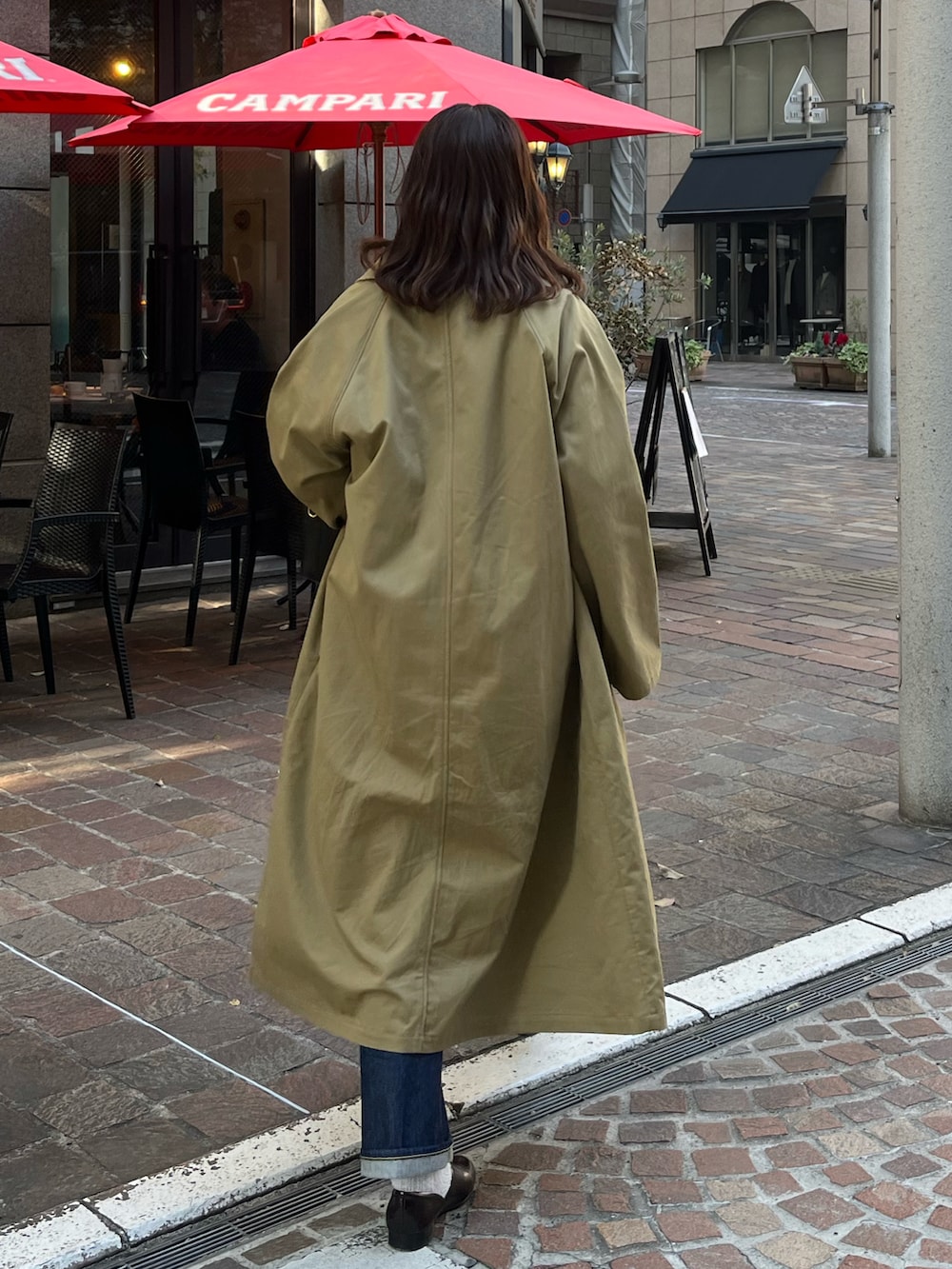 レッド系のニット/セーター、ベージュ系のステンカラーコート、ブラック系のショルダーバッグを着用したレディースの冬コーディネートの2枚目の写真