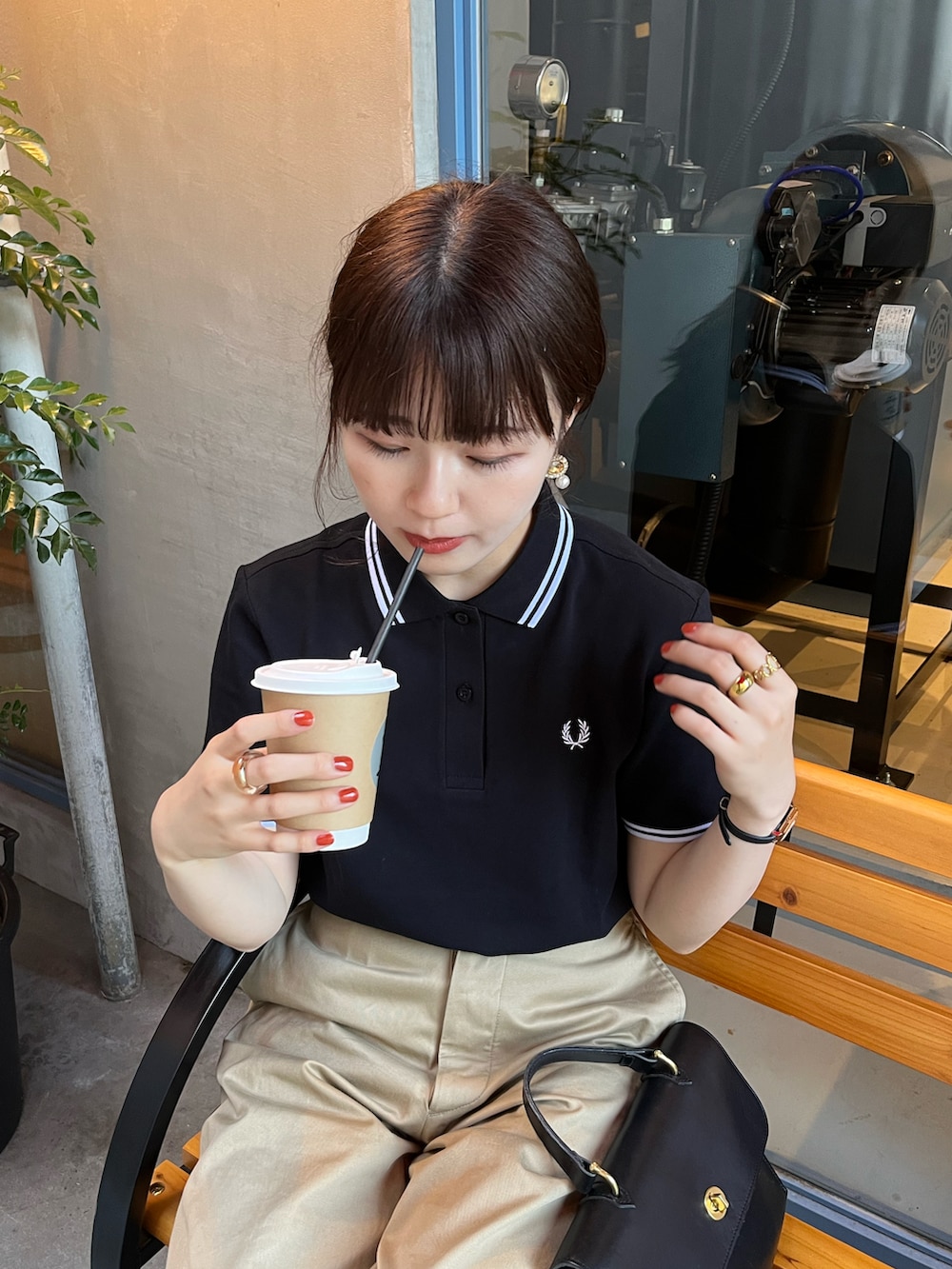 ブラック系のポロシャツ、ブラウン系のドレスシューズ、ブラック系のショルダーバッグを着用したレディースの春コーディネートの2枚目の写真