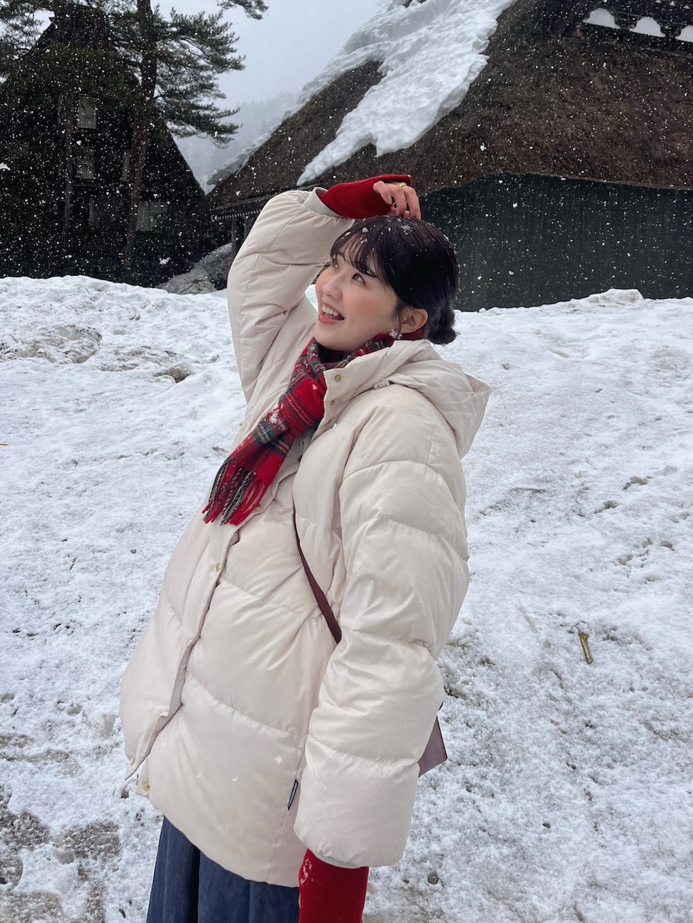 ブラウン系のブーツ、ホワイト系のダウンジャケット/コート、レッド系のショルダーバッグを着用したレディースの春コーディネートの3枚目の写真