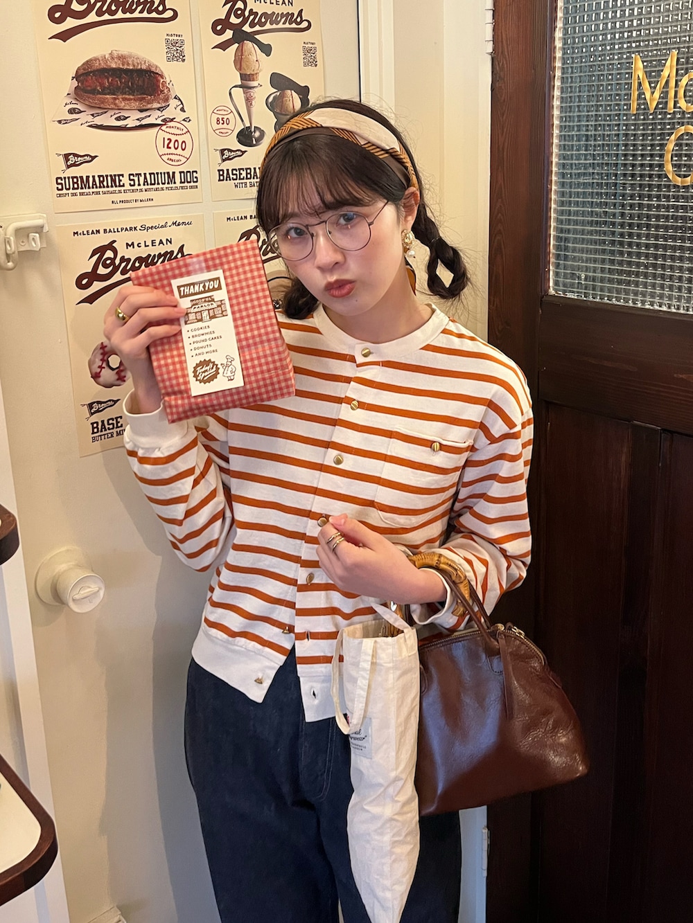ブルー系のデニムパンツ、ブラウン系のローファー、オレンジ系のカーディガン/ボレロを着用したレディースの春コーディネートの2枚目の写真
