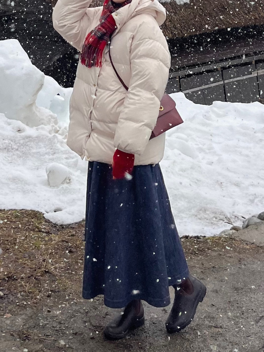 ブラウン系のブーツ、ホワイト系のダウンジャケット/コート、レッド系のショルダーバッグを着用したレディースの春コーディネートの2枚目の写真
