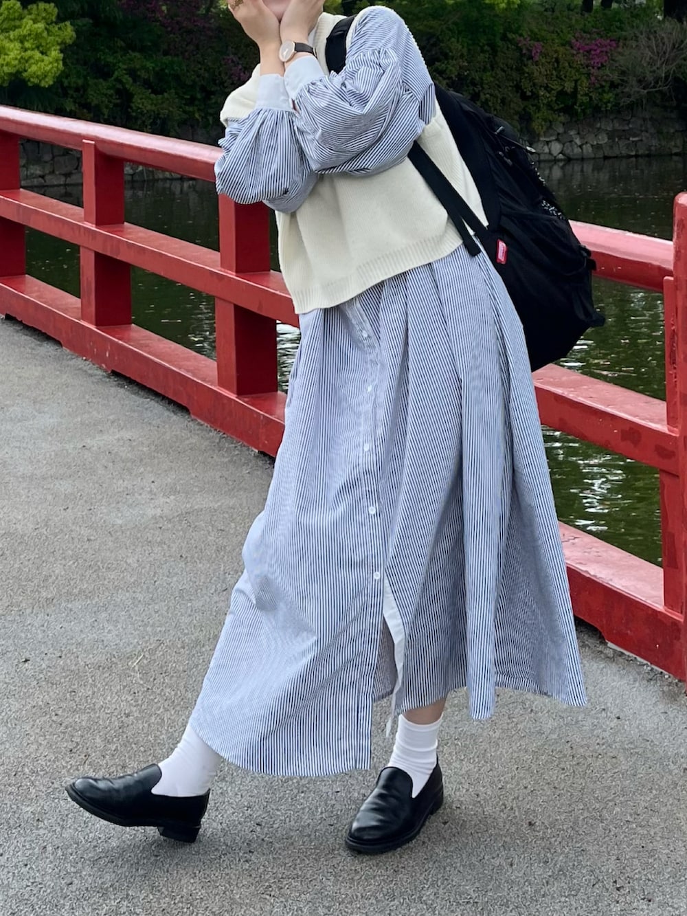 ブラック系のワンピース、ホワイト系のベスト、ブラック系のドレスシューズを着用したレディースの春コーディネートの2枚目の写真