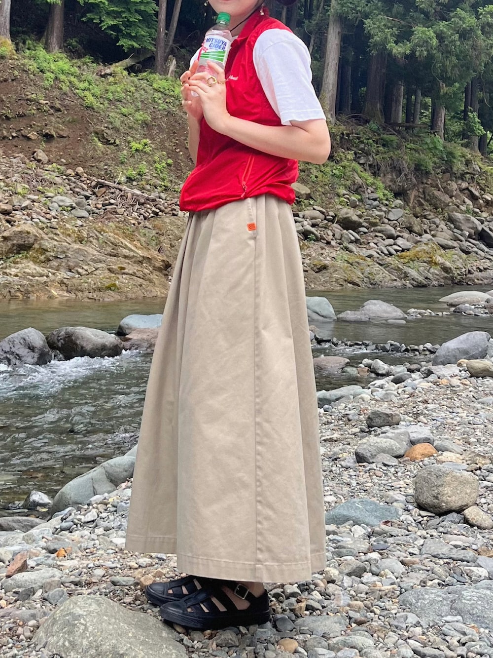 ベージュ系のスカート、ブラック系のサンダル、レッド系のベストを着用したレディースの夏コーディネートの2枚目の写真