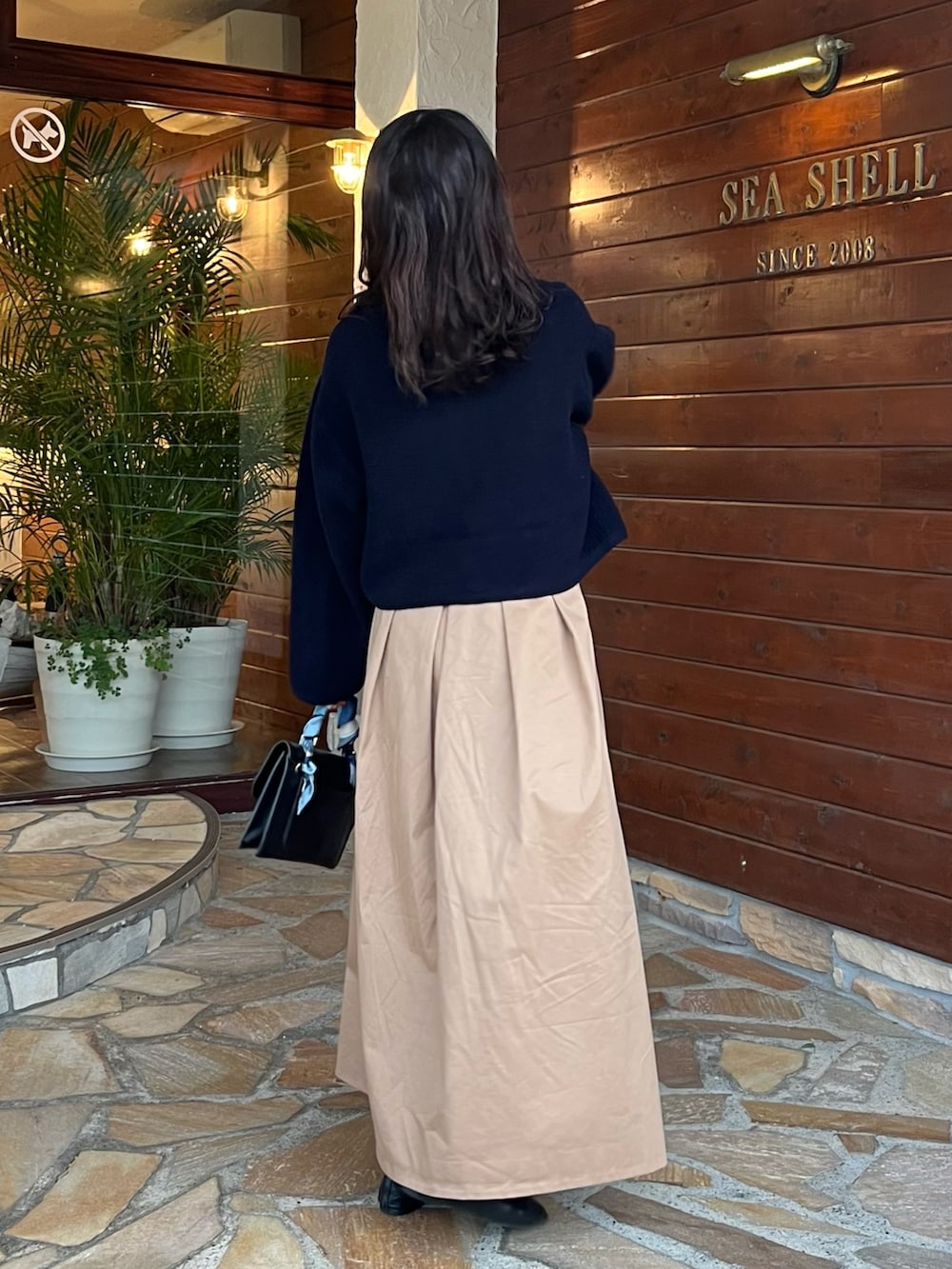 ブラック系のショルダーバッグ、ベージュ系のスカート、ブラック系のバレエシューズを着用したレディースの秋コーディネートの2枚目の写真