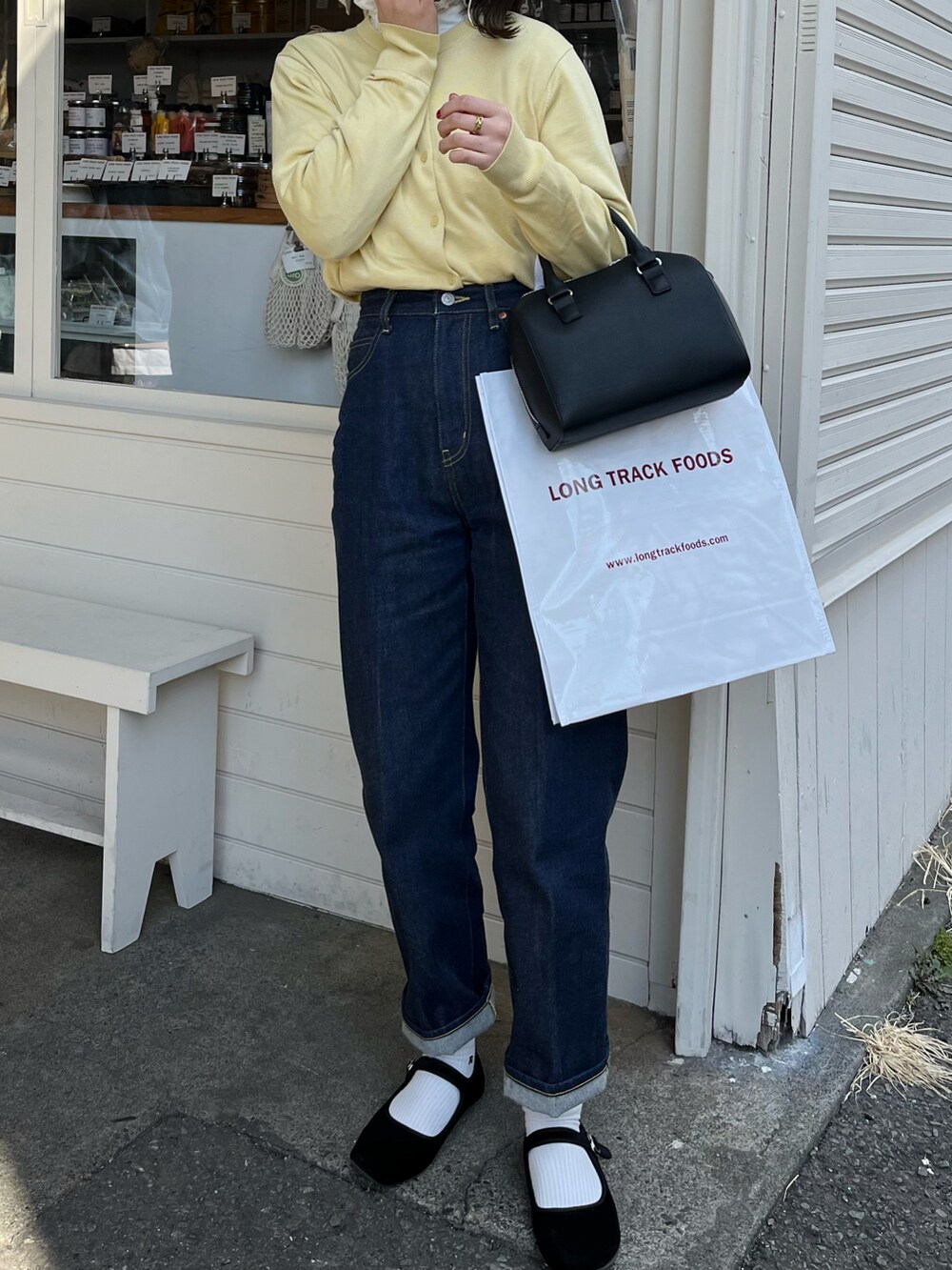 イエロー系のカーディガン/ボレロ、ブルー系のデニムパンツ、ブラック系のバレエシューズを着用したレディースの春コーディネートの2枚目の写真