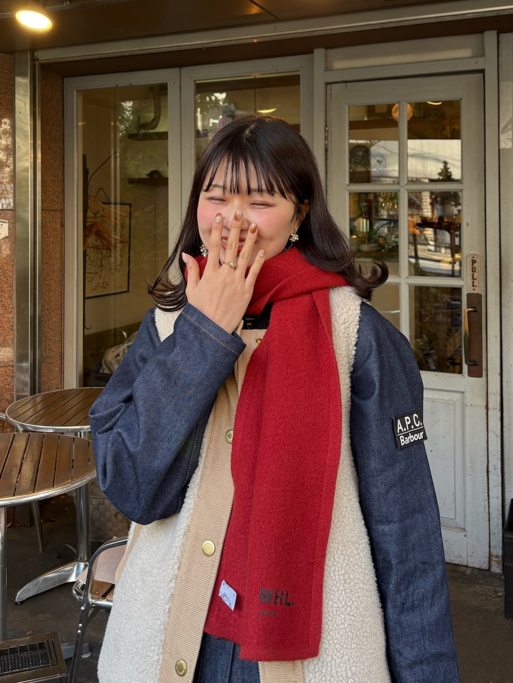 レッド系のスニーカー、ブルー系のデニムパンツ、ホワイト系のベストを着用したレディースの冬コーディネートの2枚目の写真