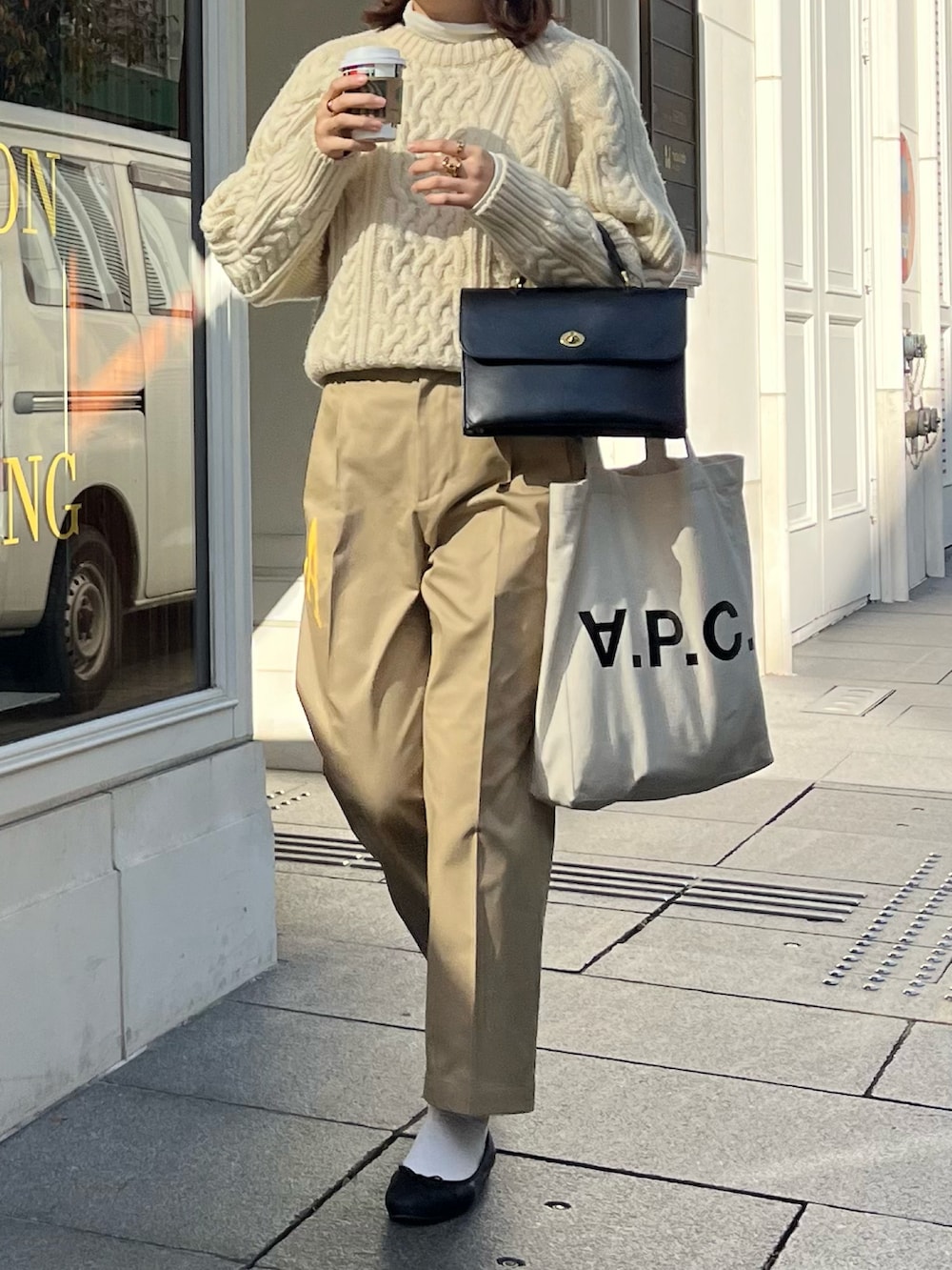 ベージュ系のチノパンツ、ホワイト系のトートバッグ、ホワイト系のニット/セーターを着用したレディースの冬コーディネートの2枚目の写真