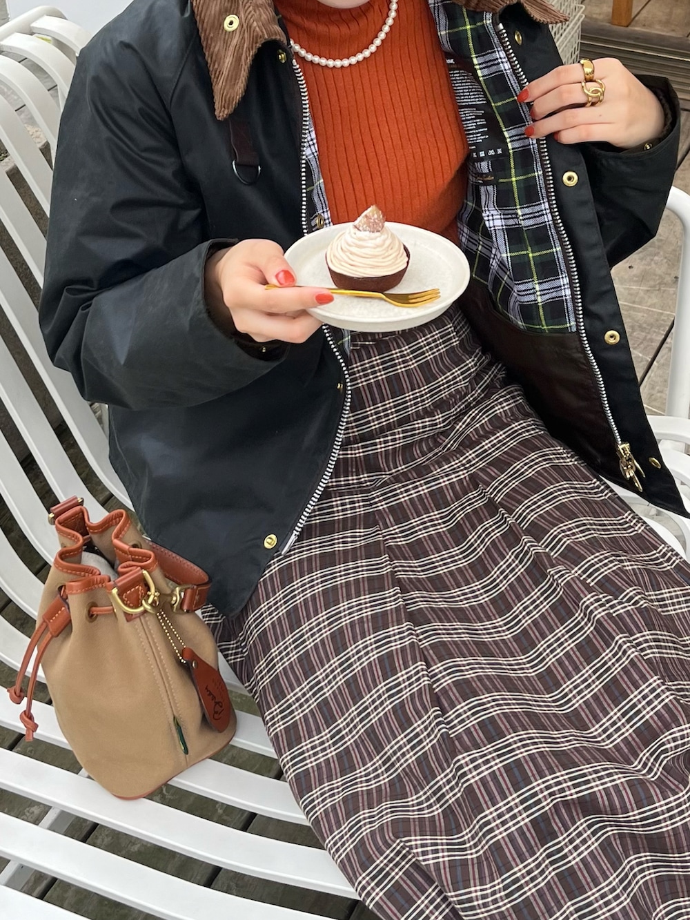 ブラウン系のスカート、グリーン系のショルダーバッグ、ブラウン系のドレスシューズを着用したレディースの秋コーディネートの2枚目の写真