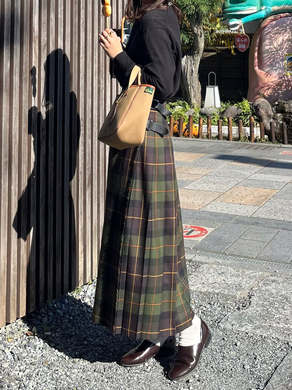 ブラウン系のドレスシューズ、グリーン系のスカート、ブラック系のカーディガン/ボレロを着用したレディースの秋コーディネートの2枚目の写真