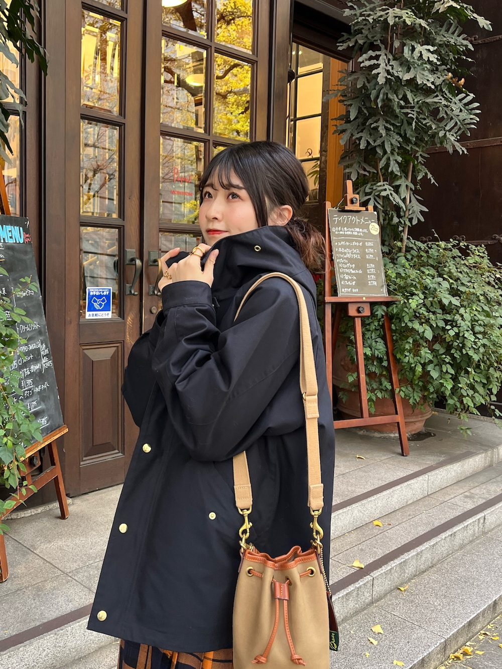 ブラック系のマウンテンパーカー、グリーン系のショルダーバッグ、オレンジ系のスカートを着用したレディースの冬コーディネートの3枚目の写真