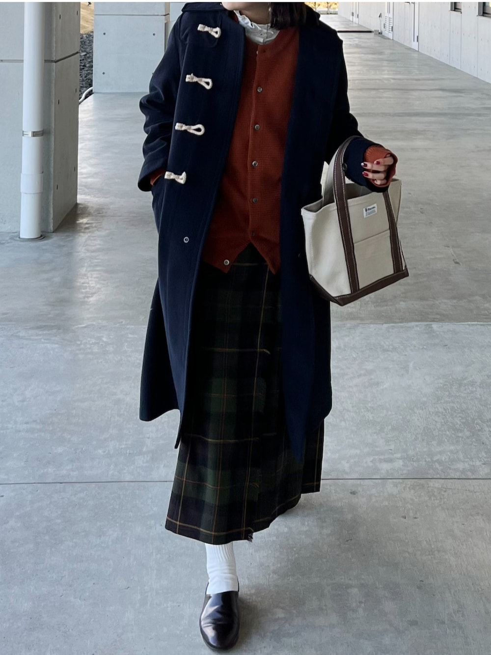 ブラウン系のトートバッグ、ブラウン系のドレスシューズ、グリーン系のスカートを着用したレディースの冬コーディネートの2枚目の写真