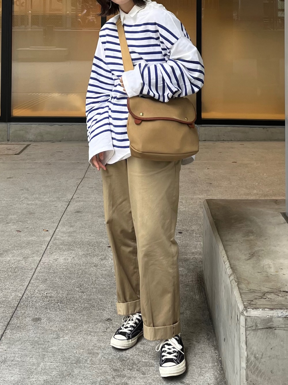 ベージュ系のショルダーバッグ、ブルー系のTシャツ/カットソー、ベージュ系のチノパンツを着用したレディースの春コーディネートの2枚目の写真