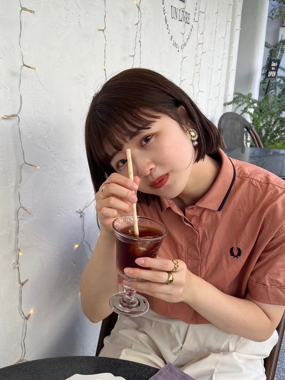 ベージュ系のバッグ、オレンジ系のシャツ/ブラウス、ホワイト系のチノパンツを着用したレディースの夏コーディネートの2枚目の写真