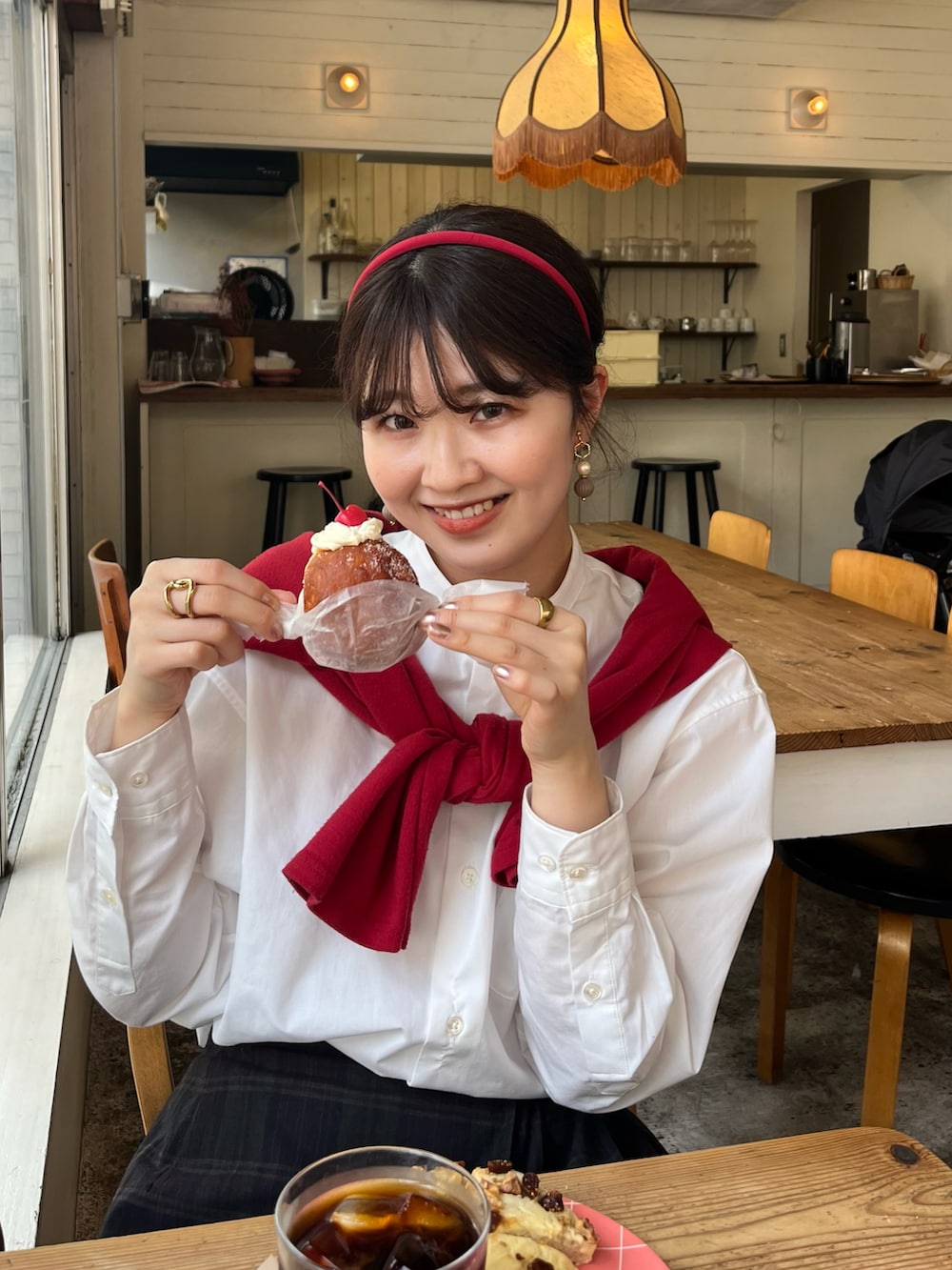 ブラック系のローファー、レッド系のショルダーバッグ、レッド系のカーディガン/ボレロを着用したレディースの春コーディネートの2枚目の写真