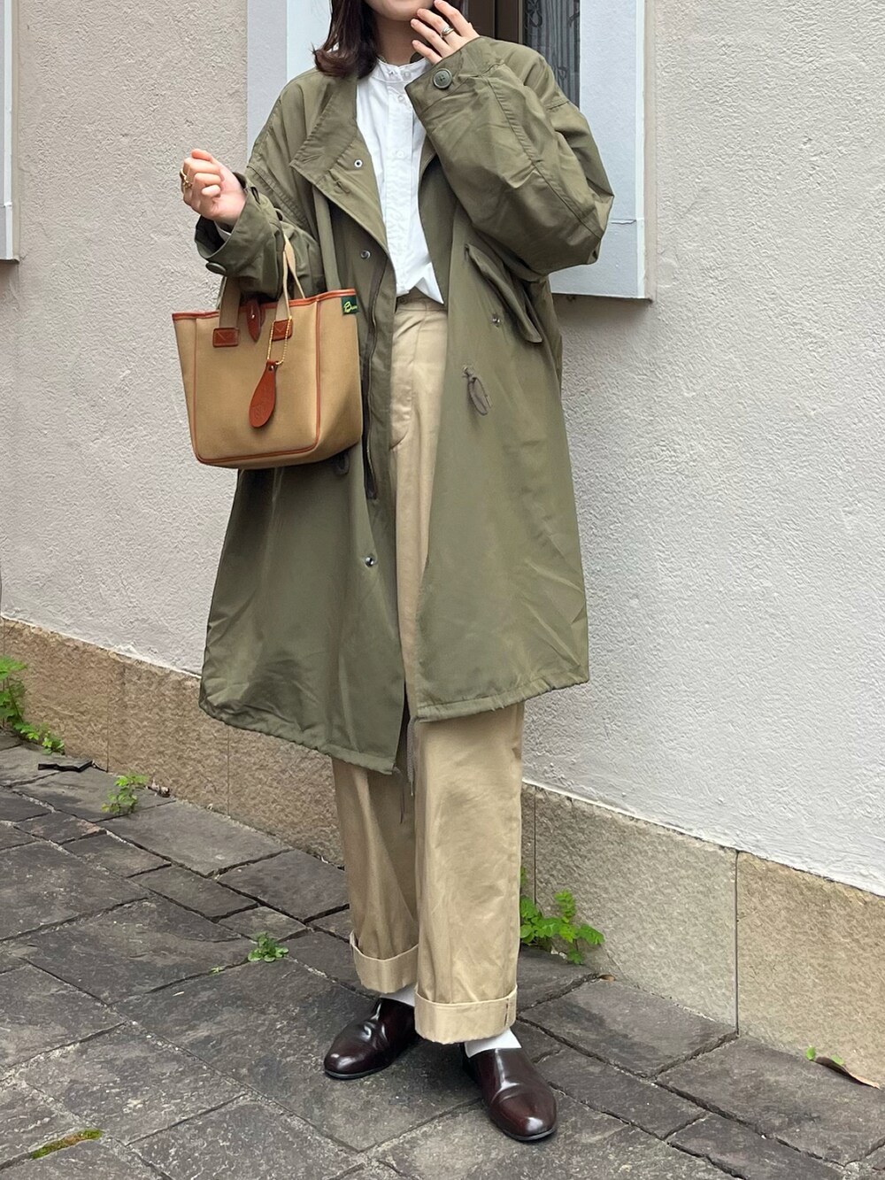 ブラウン系のドレスシューズ、ベージュ系のチノパンツ、グリーン系のトートバッグを着用したレディースの秋コーディネートの2枚目の写真