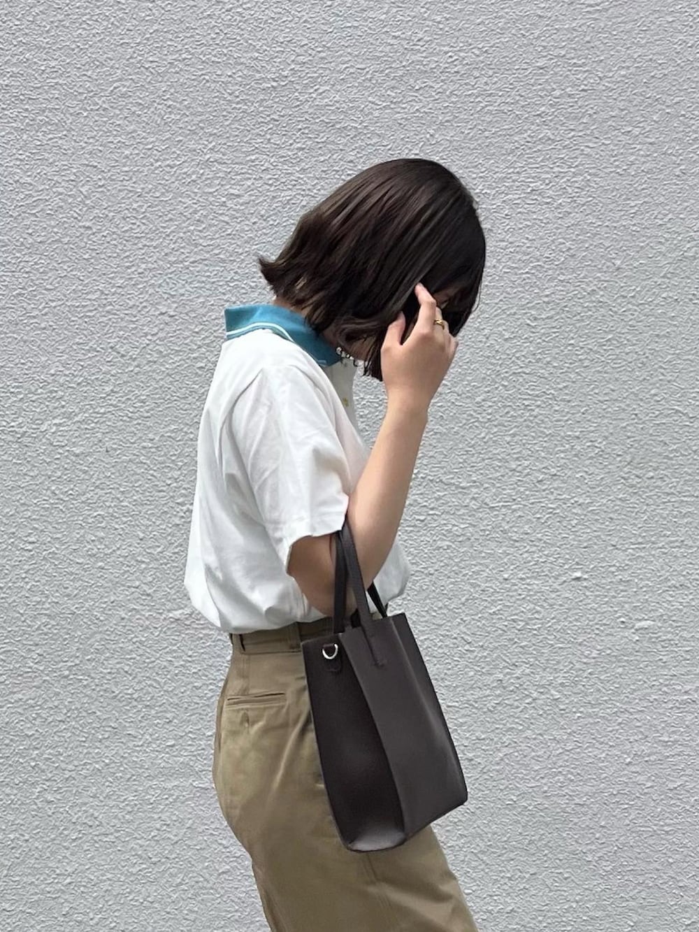 ブラウン系のショルダーバッグ、ベージュ系のチノパンツ、ブラック系のローファーを着用したレディースの春コーディネートの2枚目の写真