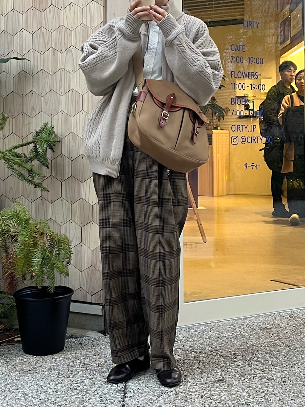 ブラウン系のスラックス、ブラウン系のドレスシューズ、グリーン系のショルダーバッグを着用したレディースの冬コーディネートの2枚目の写真