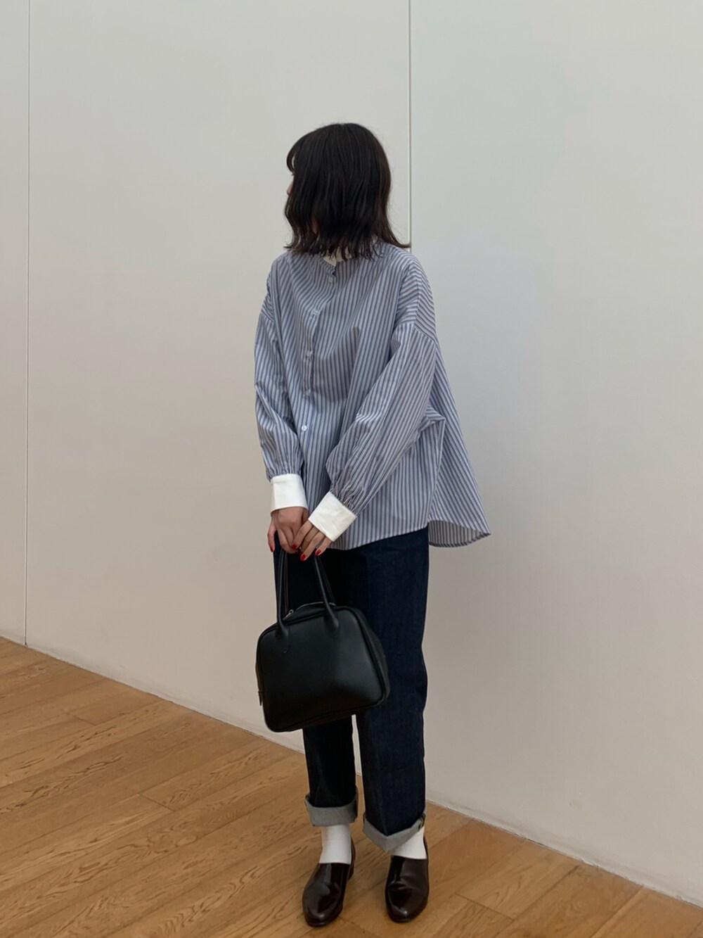 ブルー系のシャツ/ブラウス、ブルー系のデニムパンツ、ブラック系のハンドバッグを着用したレディースの春コーディネートの2枚目の写真