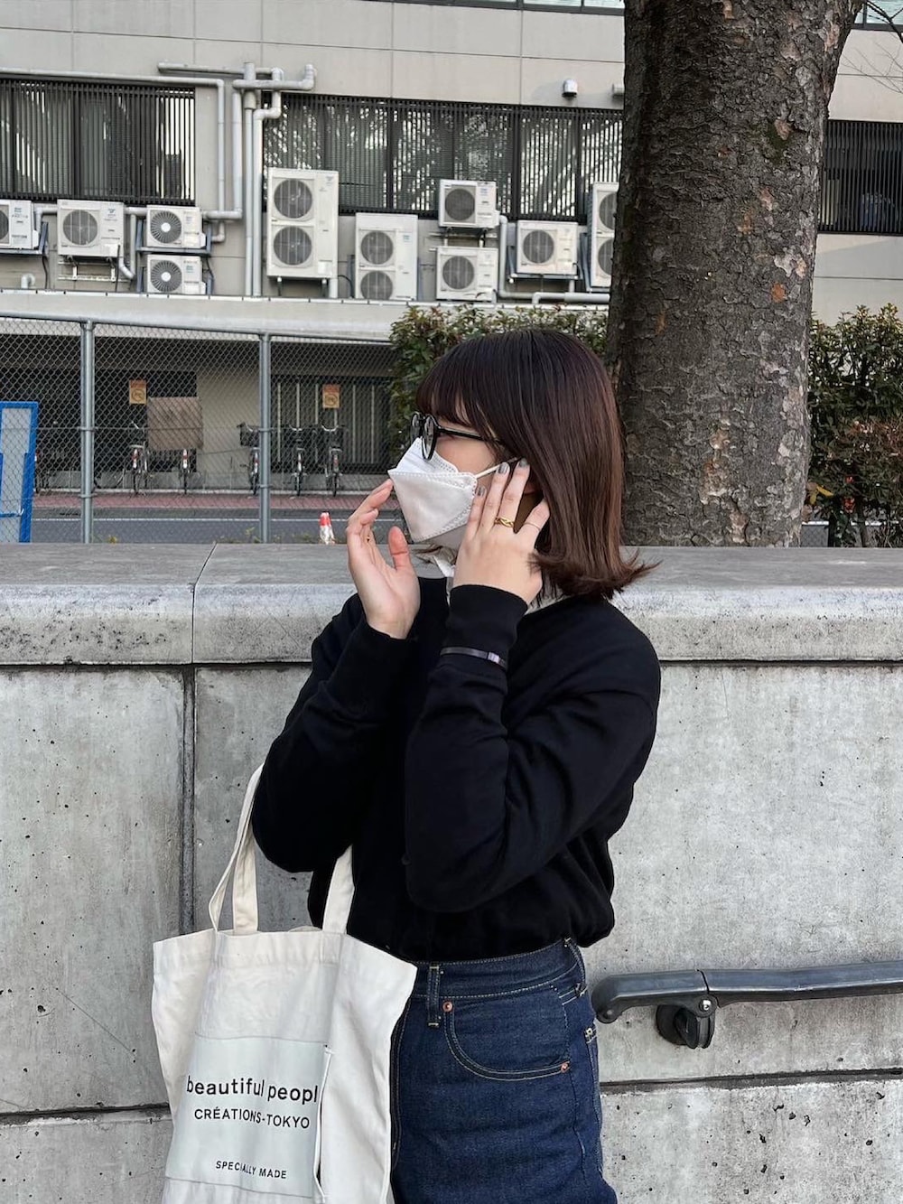 ブルー系のデニムパンツ、ホワイト系のトートバッグ、ブラック系のカーディガン/ボレロを着用したレディースの春コーディネートの4枚目の写真