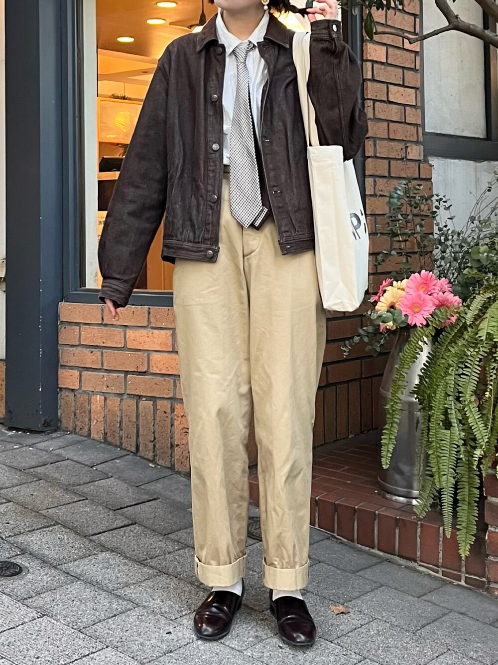 ベージュ系のチノパンツ、ブラウン系のドレスシューズ、ホワイト系のトートバッグを着用したレディースの冬コーディネートの2枚目の写真