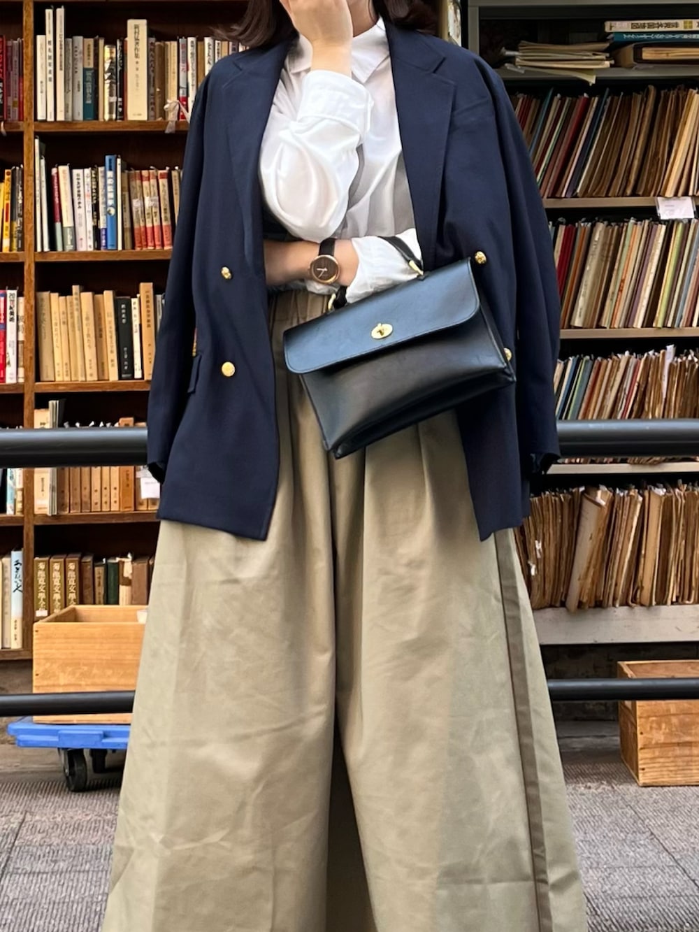 ブルー系のテーラードジャケット、ブラック系のショルダーバッグ、ベージュ系のスカートを着用したレディースの春コーディネートの2枚目の写真