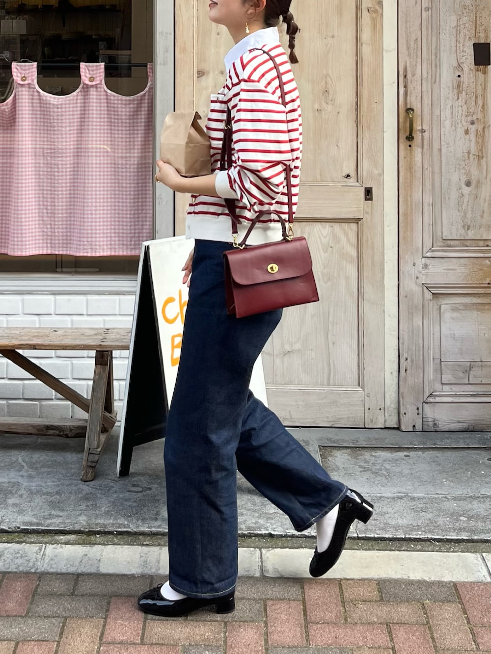 ブルー系のデニムパンツ、ブラック系のバレエシューズ、レッド系のショルダーバッグを着用したレディースの春コーディネートの2枚目の写真