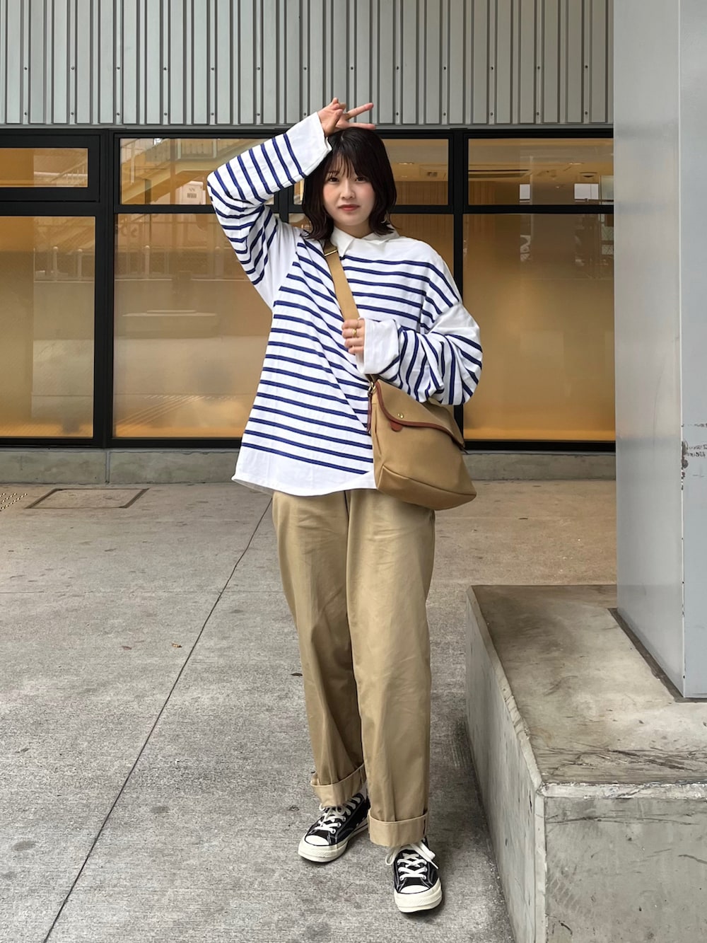 ベージュ系のショルダーバッグ、ブルー系のTシャツ/カットソー、ベージュ系のチノパンツを着用したレディースの春コーディネートの3枚目の写真