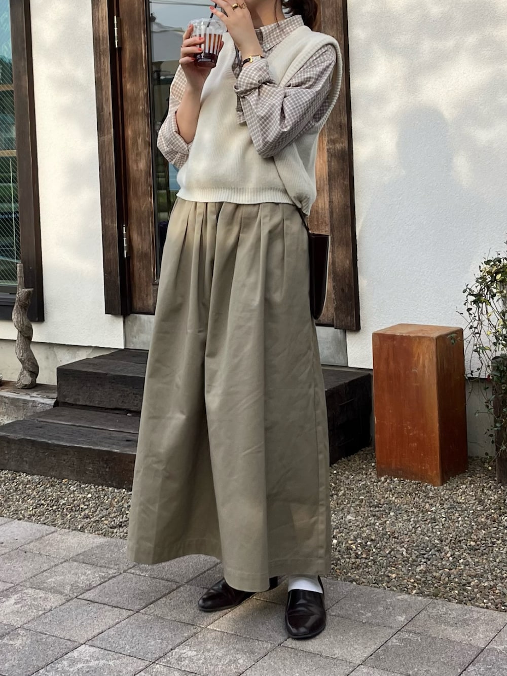 ベージュ系のスカート、ブラウン系のドレスシューズ、ブラウン系のショルダーバッグを着用したレディースの春コーディネートの2枚目の写真