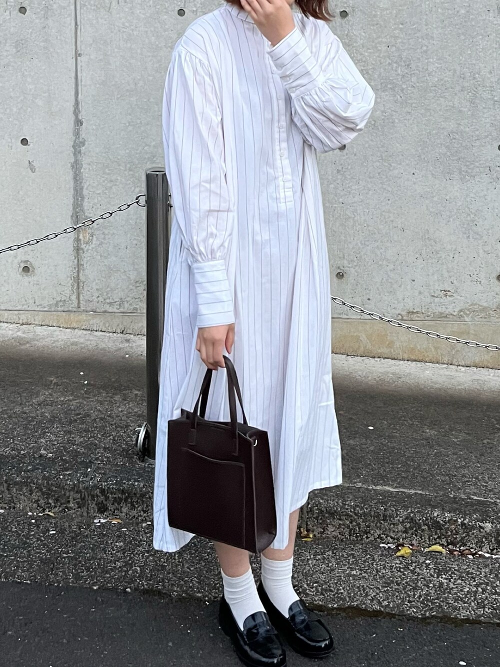 ブラウン系のショルダーバッグ、ホワイト系のワンピース、ブラック系のローファーを着用したレディースの春コーディネートの2枚目の写真