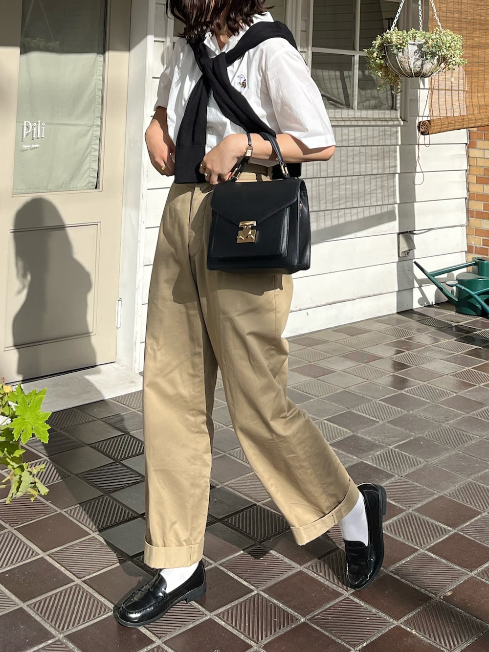 ブラック系のトートバッグ、ベージュ系のチノパンツ、ホワイト系のシャツ/ブラウスを着用したレディースの夏コーディネートの2枚目の写真