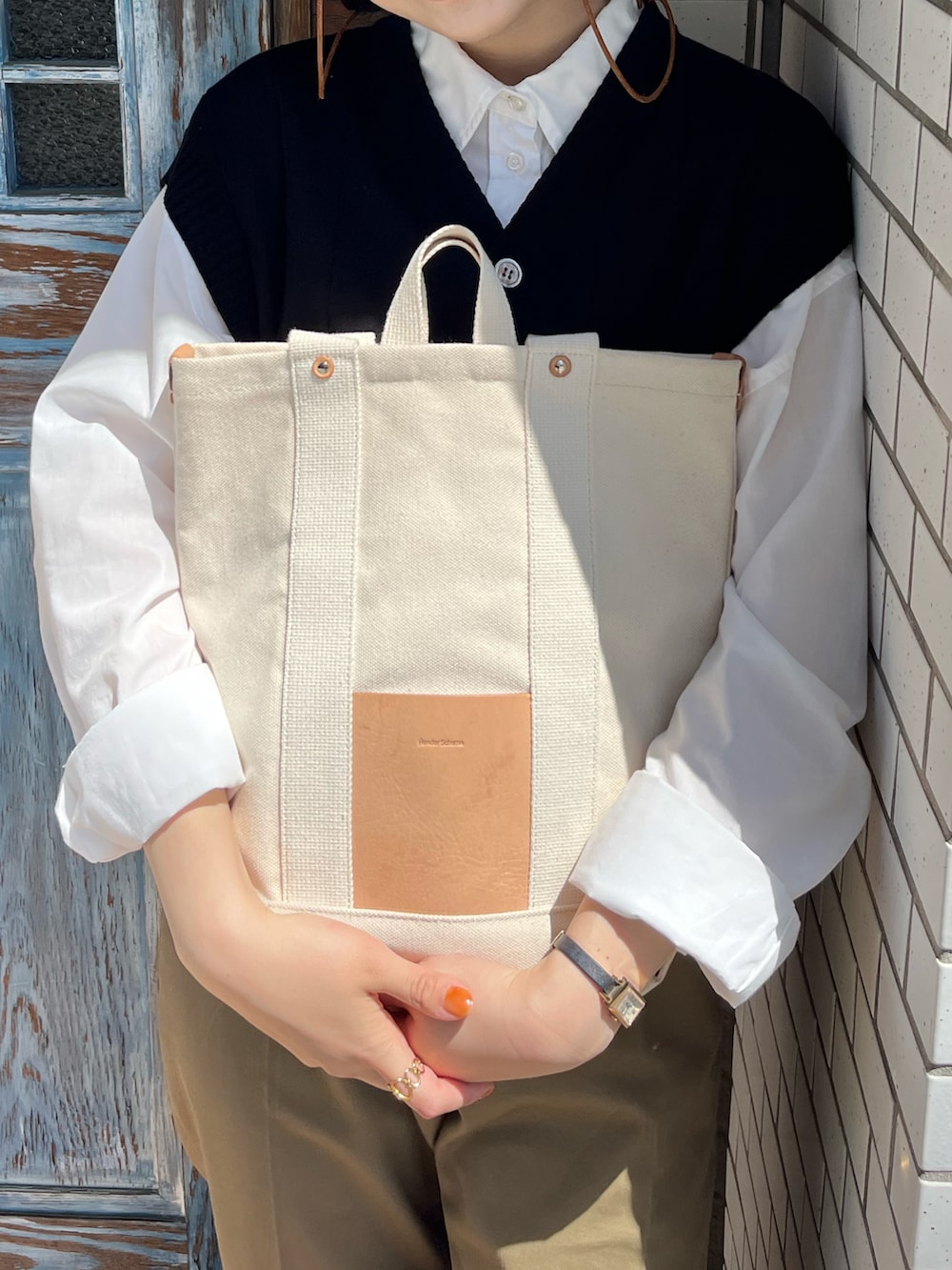 ホワイト系のシャツ/ブラウス、ベージュ系のチノパンツ、ベージュ系のトートバッグを着用したレディースの春コーディネートの2枚目の写真