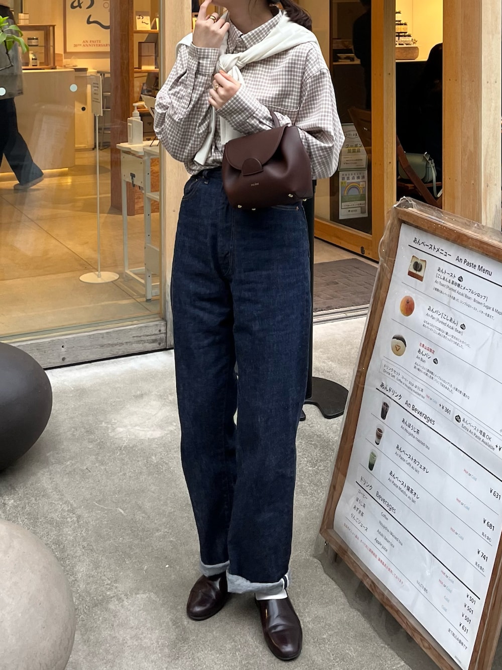 ベージュ系のシャツ/ブラウス、ブラウン系のボストンバッグ、ブルー系のデニムパンツを着用したレディースの春コーディネートの2枚目の写真