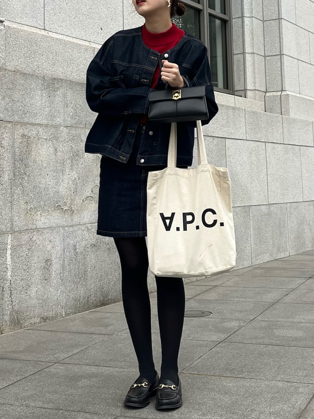 ホワイト系のトートバッグ、ブルー系のデニムスカート、ブラック系のローファーを着用したレディースの秋コーディネートの2枚目の写真