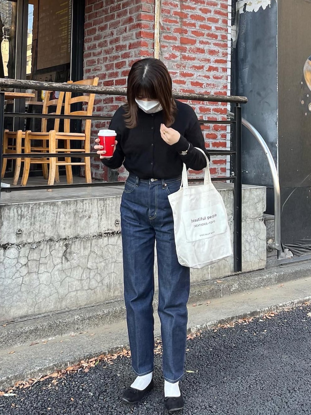 ブルー系のデニムパンツ、ホワイト系のトートバッグ、ブラック系のカーディガン/ボレロを着用したレディースの春コーディネートの2枚目の写真