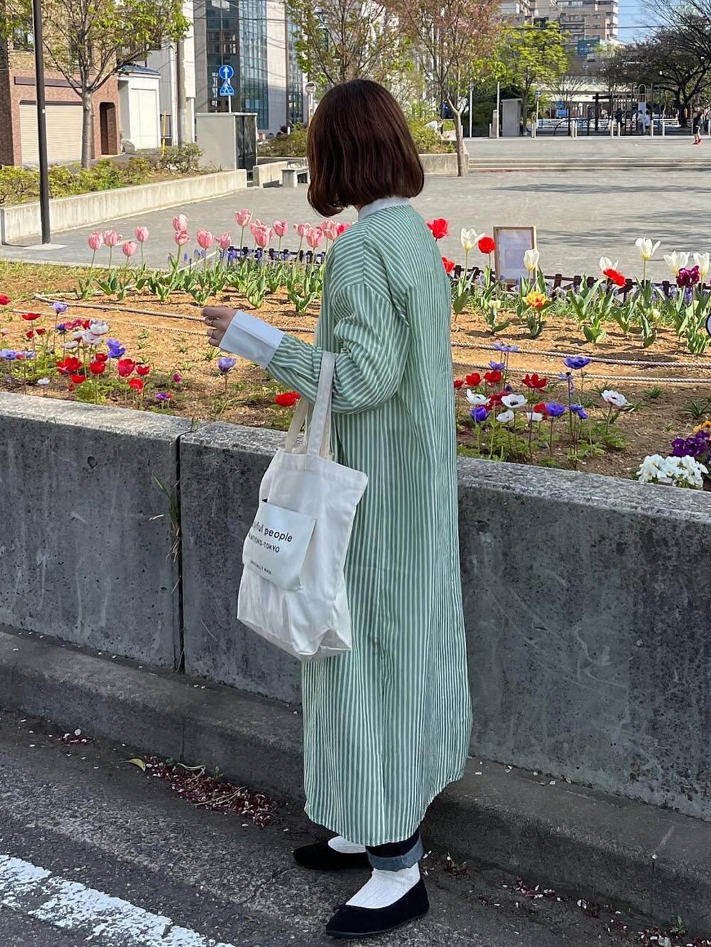 ブラック系のバレエシューズ、ホワイト系のトートバッグ、グリーン系のワンピースを着用したレディースの春コーディネートの2枚目の写真