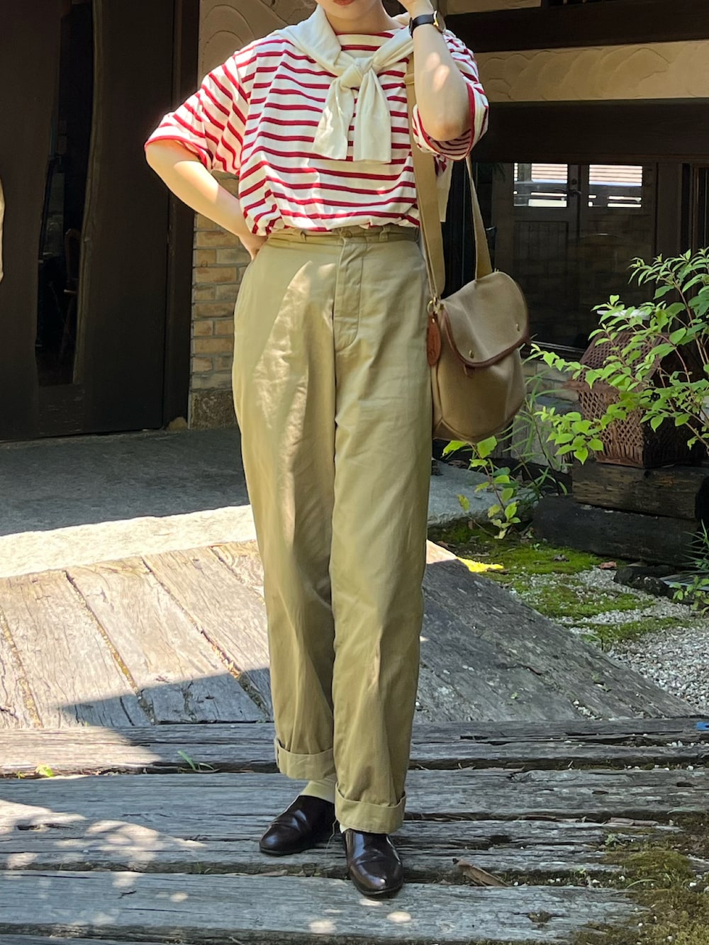 レッド系のTシャツ/カットソー、ベージュ系のチノパンツ、ブラウン系のドレスシューズを着用したレディースの夏コーディネートの2枚目の写真