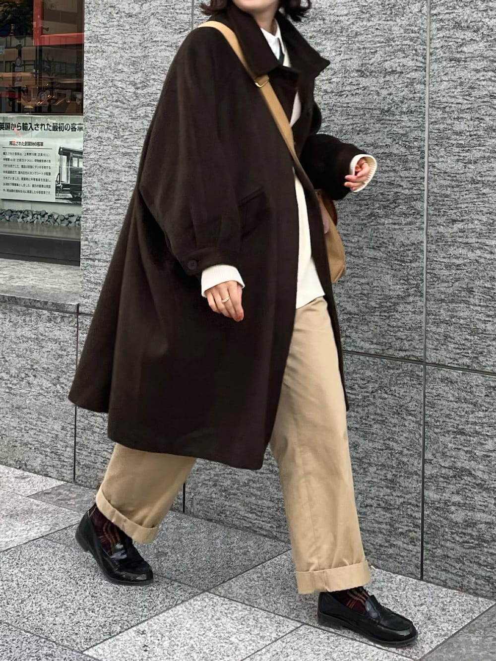 ベージュ系のチノパンツ、ブラック系のローファー、ベージュ系のショルダーバッグを着用したレディースの冬コーディネートの2枚目の写真