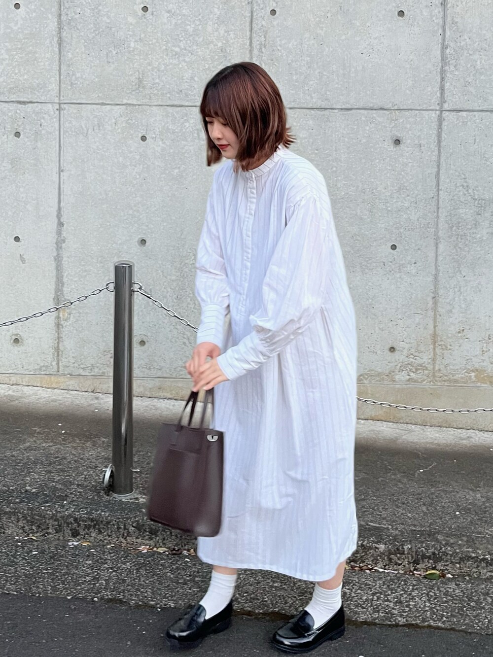 ブラウン系のショルダーバッグ、ホワイト系のワンピース、ブラック系のローファーを着用したレディースの春コーディネートの3枚目の写真